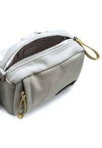 Bolsa de tela gris con una textura suave, apertura con cremallera y detalles en oro. El interior está forrado en un material oscuro y cuenta con un pequeño bolsillo.