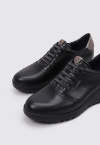 Chaussures en cuir noir avec une finition lisse, lacets tressés et un talon mat contrastant. Semelle en caoutchouc avec une légère plateforme pour plus de hauteur.