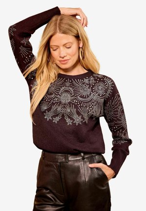 Dunkellila gestrickter Pullover mit aufwendigen silbernen Verzierungen im Muster von Sternen und Wirbeln, langen Ärmeln und einem Rundhalsdesign.