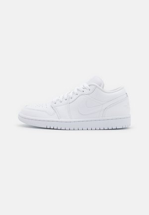 Baskets basses blanches en cuir avec bout perforé, fermeture à lacets et logo Nike discret sur le côté.