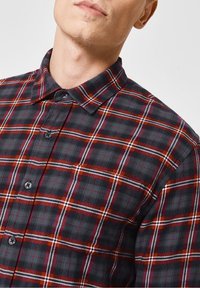 Zwart-rood ruitjesoverhemd met knopen, voorzien van een klassieke kraag, knoopsluiting en een gestructureerde stof met contrasterende witte strepen.