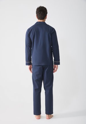 Navy blue pajama set featuring a long-sleeve top with a collar and piped accents, paired with matching straight-leg pants.