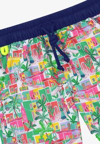 Shorts de bain avec un imprimé de bâtiment vibrant et multicolore. Dotés d'une taille élastique bleue avec un cordon de serrage et des accents de feuilles de palmier.