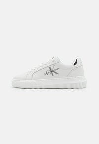 Sneaker bianca realizzata in materiale liscio, con punta rotonda, suola spessa bianca e dettagli argentati con il logo "Calvin Klein Jeans" sul lato.