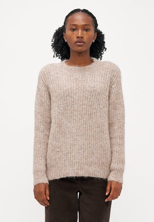 Beige strikket genser med ribbet tekstur, rund hals og lange ermer. Mykt materiale med en litt løs passform, brukt over mørke cordfløyelsbukser.