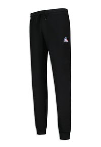 Svarta sweatpants i bomullsmaterial med dragsko i midjan, smalnande ben och en liten flerfärgad logga på vänster sida.