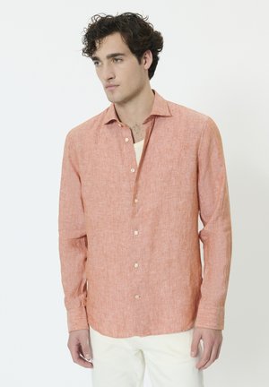 Chemise en lin orange clair à manches longues, avec un devant boutonné et un col légèrement ouvert. Tissu texturé et boutons de couleur crème.