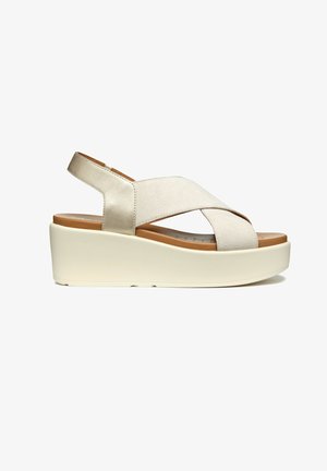 Beige wedge sandalen met kruisbanden van zacht materiaal, gevoerd voetbed en een dikke, witte platformzool voor extra hoogte en comfort.