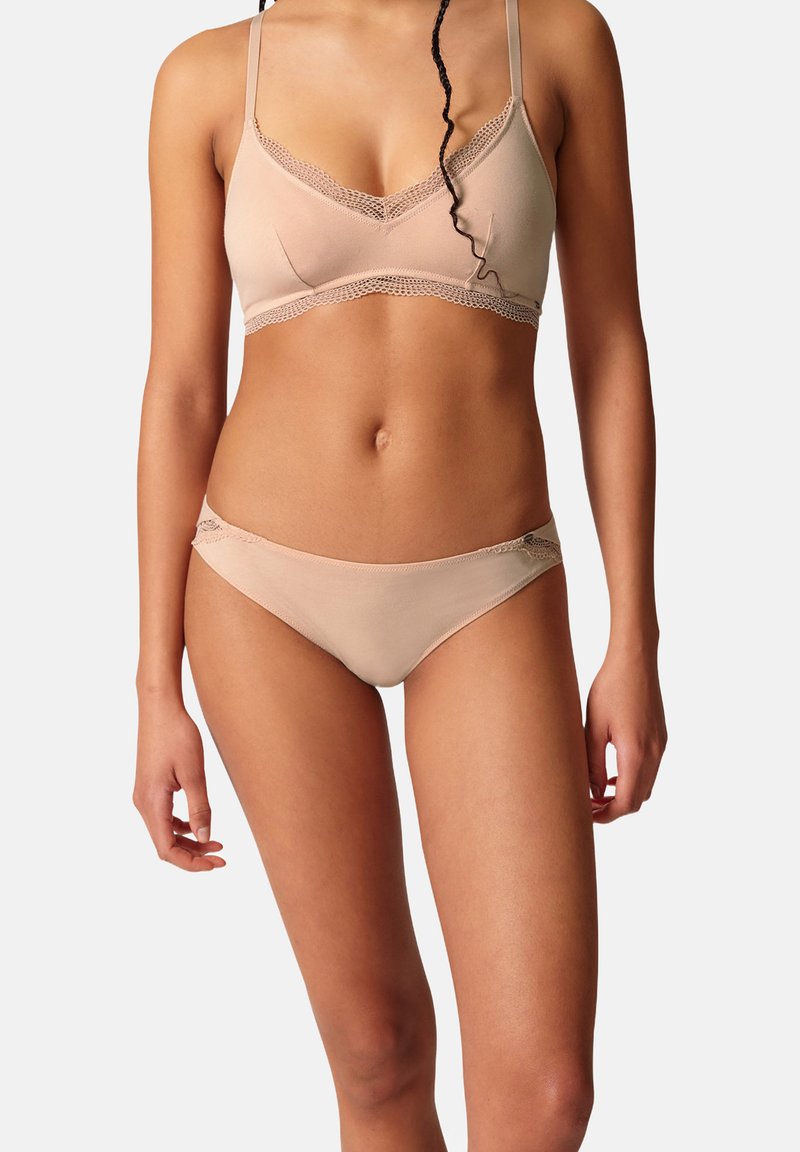 BH- und Bikini-Set in hell-nudefarbener Farbe, aus weichem Stoff gefertigt. Beide Teile besitzen zarte Spitzenverzierungen und ein nahtloses Design.