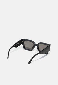 Black sunglasses with dark lenses, rectangular frame, glossy plastic material, angular design, straight arms, and logo detail on the temple.