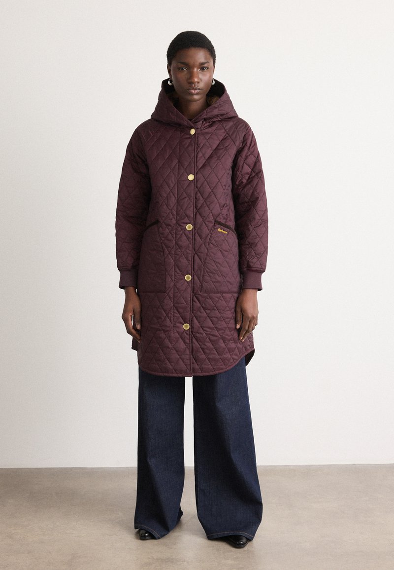 Gequilte lange jas in donkerburgundy, voorzien van een capuchon, knopen aan de voorkant, twee zijzakken en gouden hardware accenten. Textuurstof.