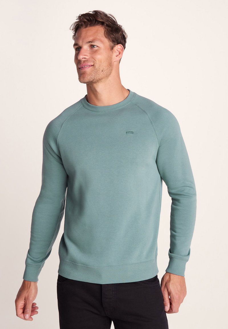 Light teal sweatshirt made of soft fabric, featuring a crewneck, ribbed cuffs, and a fitted hem. Small logo on the left chest.