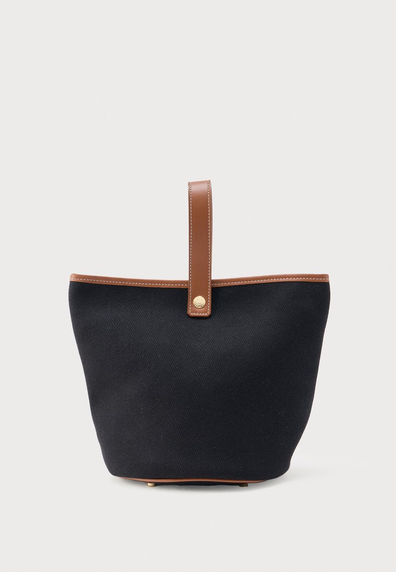 Μαύρη υφασμάτινη τσάντα tote με καφέ δερμάτινο λουράκι και περιθώρια, με χρυσή λεπτομέρεια κουμπιού στο λουράκι.