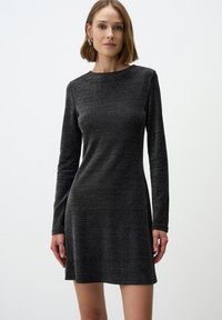Abito nero a maniche lunghe con superficie testurizzata, caratterizzato da una scollatura rotonda e una silhouette aderente che si allarga leggermente all'orlo.