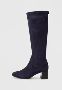 Bottes en suede violettes jusqu'au genou avec un bout rond, un talon carré et des accents de couture le long des coutures pour un détail supplémentaire.