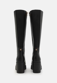 Botas negras de cuero hasta la rodilla con un acabado suave, que cuentan con cierre de cremallera, panel texturizado y un tacón grueso.
