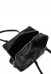 Sac à main en cuir noir avec une fermeture éclair sur le dessus, deux poignées et des accessoires en métal. L'intérieur est sombre avec aucun compartiment visible.