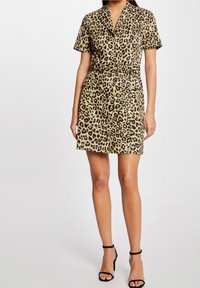 Beżowa sukienka w zwierzęcy wzór w cętki, z krótkimi rękawami, z guzikami z przodu, z paskiem w talii i dwiema kieszeniami z przodu. Gładka tekstura.