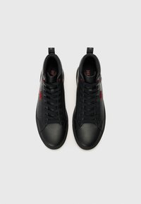 Baskets en cuir noir avec une finition lisse, des accents rouges contrastants et une semelle en caoutchouc plate avec des lacets pour un maintien sûr.