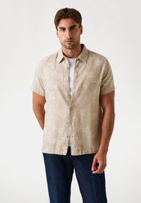 Camisa de manga corta, color beige claro, con un diseño de hojas. Fabricada en tejido ligero, cuenta con un cierre de botones en la parte delantera y un cuello clásico.