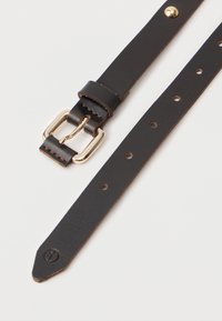 Hnědý kožený pásek se zlatou kovovou sponou, s několika úpravnými dírkami a dekoračním embosovaným logem blízko špičky.