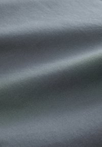 Tejido gris con una textura suave y un brillo sutil. Presenta un patrón de tejido diagonal. Apariencia suave, ligera y maleable.