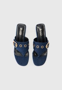 Sandales à glissière en denim avec un tissu bleu marine, un design ouvert à l'avant, des accents en métal doré et une semelle intérieure noire arborant le nom de la marque "RAID."