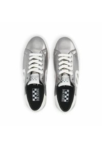 Metallic silver sneakers with white laces, featuring a contrasting white heel and side logo. Black insoles with a checkered pattern.