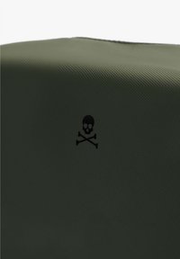 Un material texturizado verde presenta un emblema de calavera y huesos cruzados en negro, enfatizando un elemento de diseño audaz en la superficie.