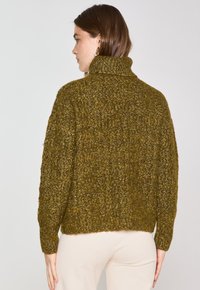 Maglione lavorato a maglia verde oliva con una consistenza spessa, colletto alto e polsini a coste. Design corto e dal taglio rilassato, caratterizzato da punti larghi.