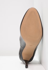 Černá kožená lodička na vysokém podpatku s špičatou špičkou, vyznačující se hladkým svrškem, texturovanou podrážkou a tenkým stiletto podpatkem. Velikost 37 označena uvnitř.