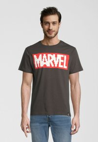 Grå bomulls T-shirt med en stor röd och vit "MARVEL" grafik på framsidan. Klassisk rund halsringning och korta ärmar. Avslappnad passform.
