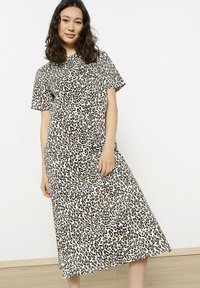 Kurzärmliges Kleid mit Leopardenmuster in Beige, Schwarz und Braun. Knielang mit geradem Schnitt und weichem, glattem Stoffgefühl.
