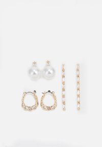 Trois paires de boucles d'oreilles : de grandes perles blanches en boutons, des créoles en or avec des pierres claires, et deux longues boucles d'oreilles droites en or avec des détails scintillants.