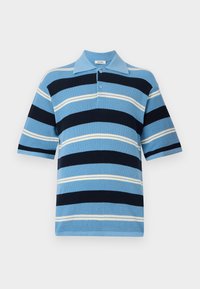 Csíkos póló inget visel, világoskék, tengerészkék és fehér színekben. Rövid ujjú, galléros, gombos nyitással; texturált kötött anyag különböző szélességű csíkokkal.