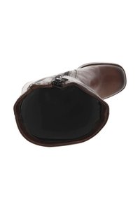 Bottine en cuir marron avec une finition lisse, à bout carré et à détails zippés. La doublure intérieure est noire, mettant en avant une forme arrondie et spacieuse.