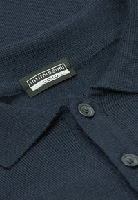 Granatowa koszulka polo o prążkowanej fakturze, z kołnierzykiem, dwoma czarnymi guzikami oraz metką "Intimissimi Uomo" przy dekolcie.