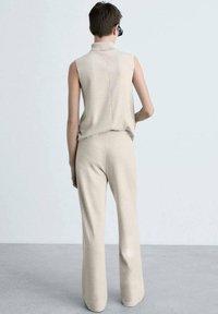 Beige ärmelloses Rollkragenoberteil und passendes weites Bein-Hosen, aus weichem Material gefertigt, mit entspannter Passform und minimalistischem Design.