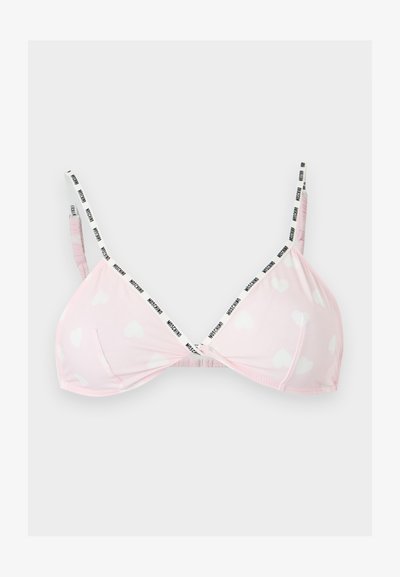 Ανοιχτό ροζ bralette με λευκά σχέδια καρδιών και λεπτές ασπρόμαυρες λωρίδες με λογότυπο, απλωμένο επίπεδα σε γκρίζο φόντο.