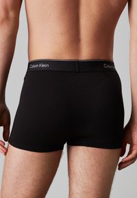 Zwarte katoenen boxershorts met een elastische tailleband met witte "Calvin Klein" branding. Glad textuur, strakke pasvorm, lengte tot halverwege de bovenbenen.