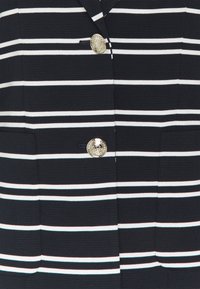 Marynarka w paski w kolorze granatowym i białym, wykonana z teksturowanej tkaniny, z dwoma przednimi kieszeniami i złotym okrągłym guzikiem.