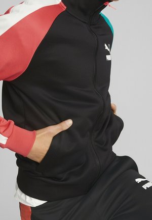 Zwarte sportieve zip-up jack met rode en turquoise accenten. Voorzien van een hoge kraag, geribbelde manchetten en zijzakken. Logo zichtbaar op de borst.