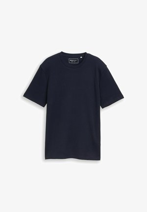 Tengerészkék rövid ujjú, kerek nyakú póló rendszeres szabással, fehér háttéren laposan elhelyezve.