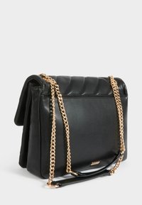 Borsa a tracolla in pelle nera con design trapuntato, dotata di una tracolla in catena dorata e una texture liscia. Chiusura a pattina con un accento di logo minimalista.