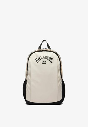 White and black Billabong backpack with front zipper pocket and black mesh side pockets, standing upright on a white background.