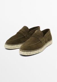 Olive green suede loafers with a stitched moccasin-style upper and a braided jute outsole for added texture and contrast.