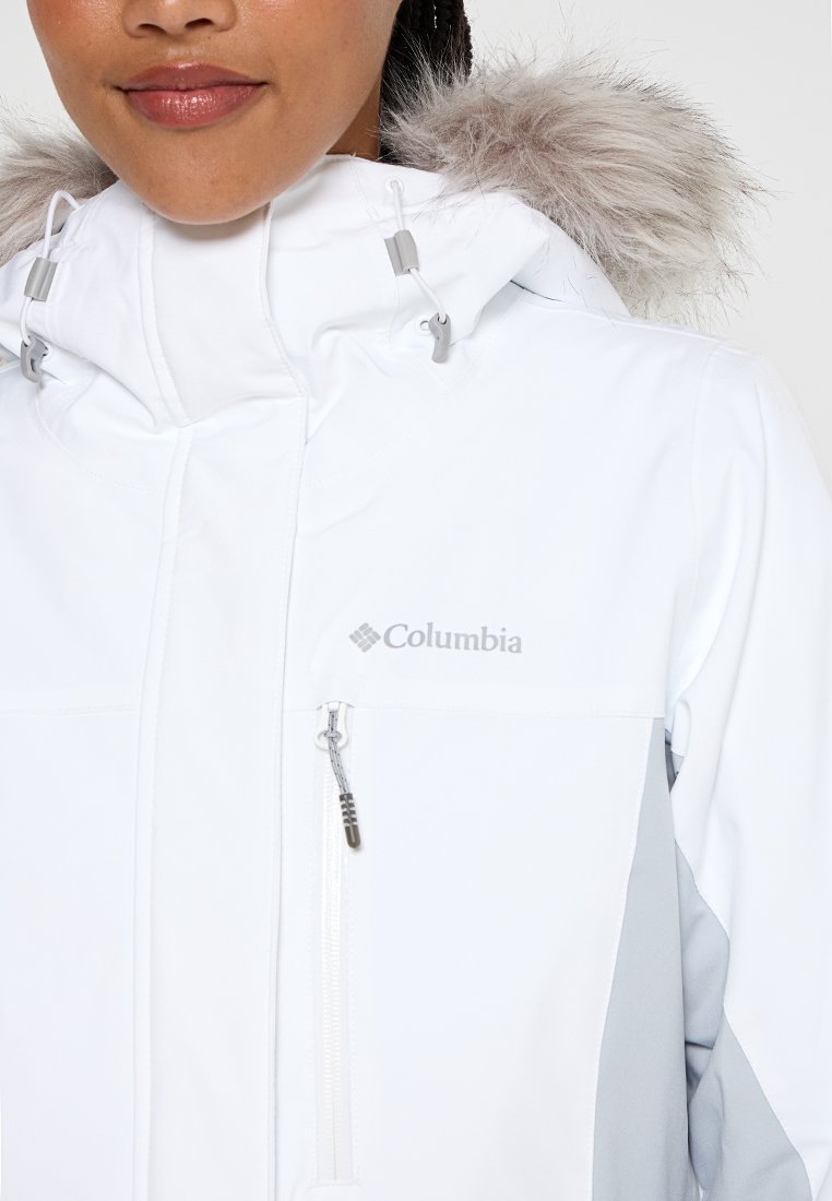 Weißer wasserdichter Jacke mit abnehmbarem grauem Kunstpelzkragen, Frontreißverschluss und Columbia-Logo auf der Brust.