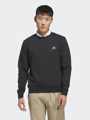 Black sweatshirt with crew neckline and ribbed cuffs, featuring a small white circular logo on the chest. Worn over a white collared shirt.