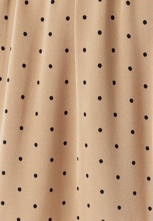 Persikkavärinen kangas, jossa on tasaisesti sijoittuneet mustat pilkut. Pehmeä rakenne ja sileä pinta, joka esittelee yksinkertaisen kuvion koko ajan.