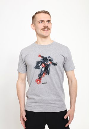 Camiseta de algodón gris con un gráfico colorido de un superhéroe en una pose dinámica con explosiones, logo mostrado en la parte inferior.